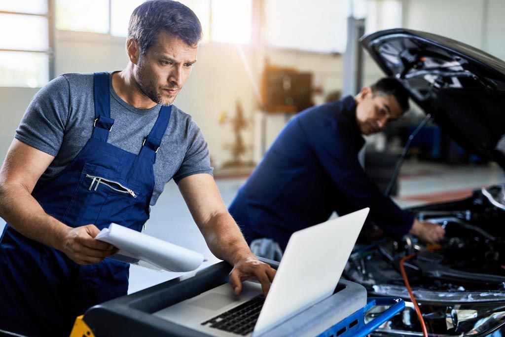 Mecánico realizando diagnóstico de vehículo con soporte digital, garantizando mantenimiento eficiente con lubricantes Shell Mecánico realizando diagnóstico de vehículo con soporte digital, garantizando mantenimiento eficiente con lubricantes Shell